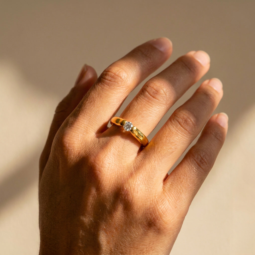 Hand wearing asymmetrical gold and platinum solitaire ring