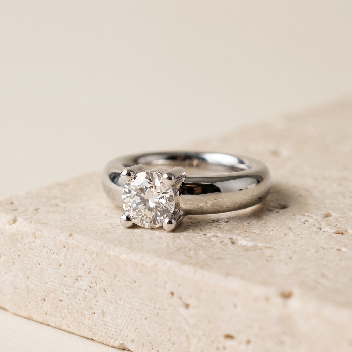 Top-down angled view of 18k white gold solitaire diamond ring with polished band