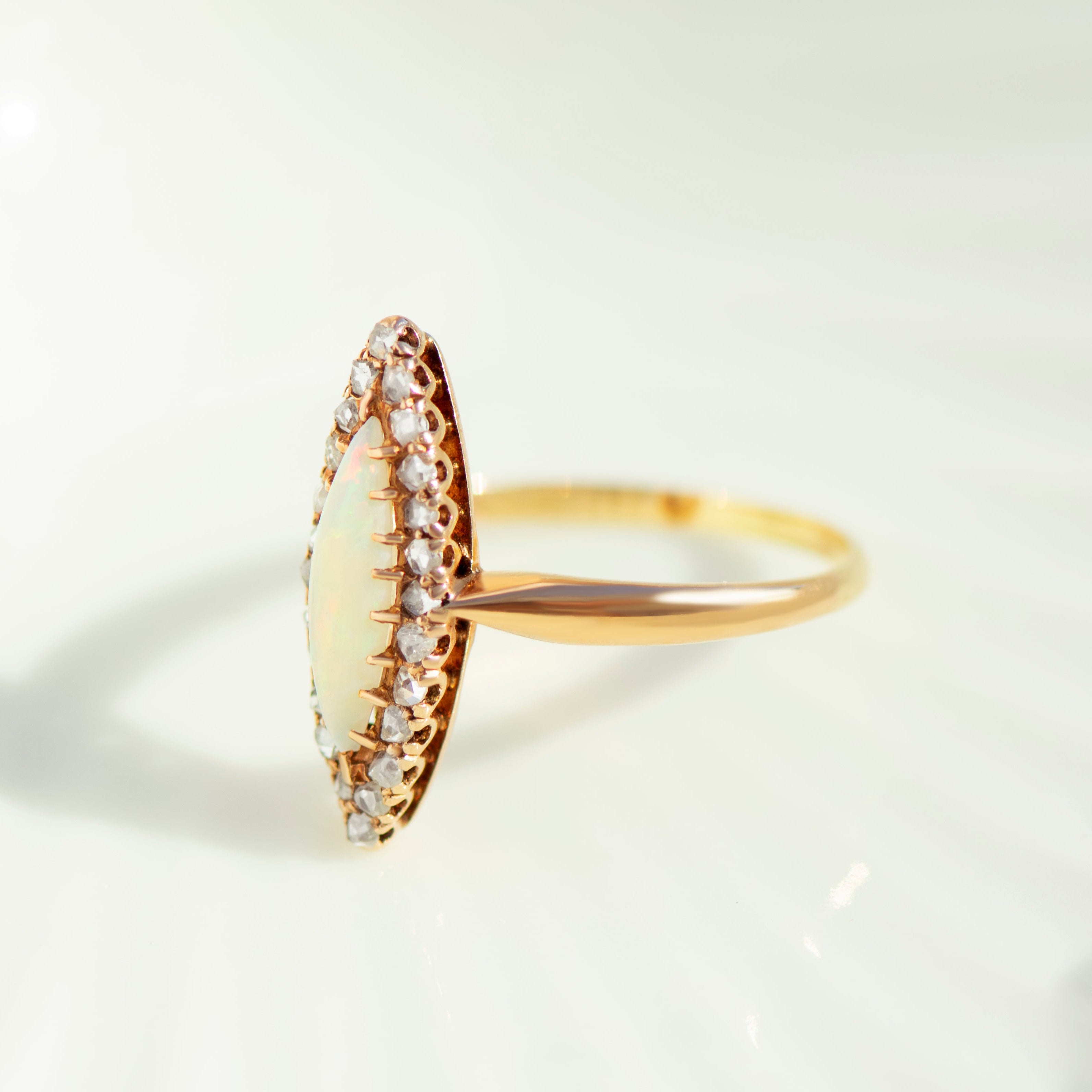 Marquise opal ring with halo of unpolished diamonds in profile