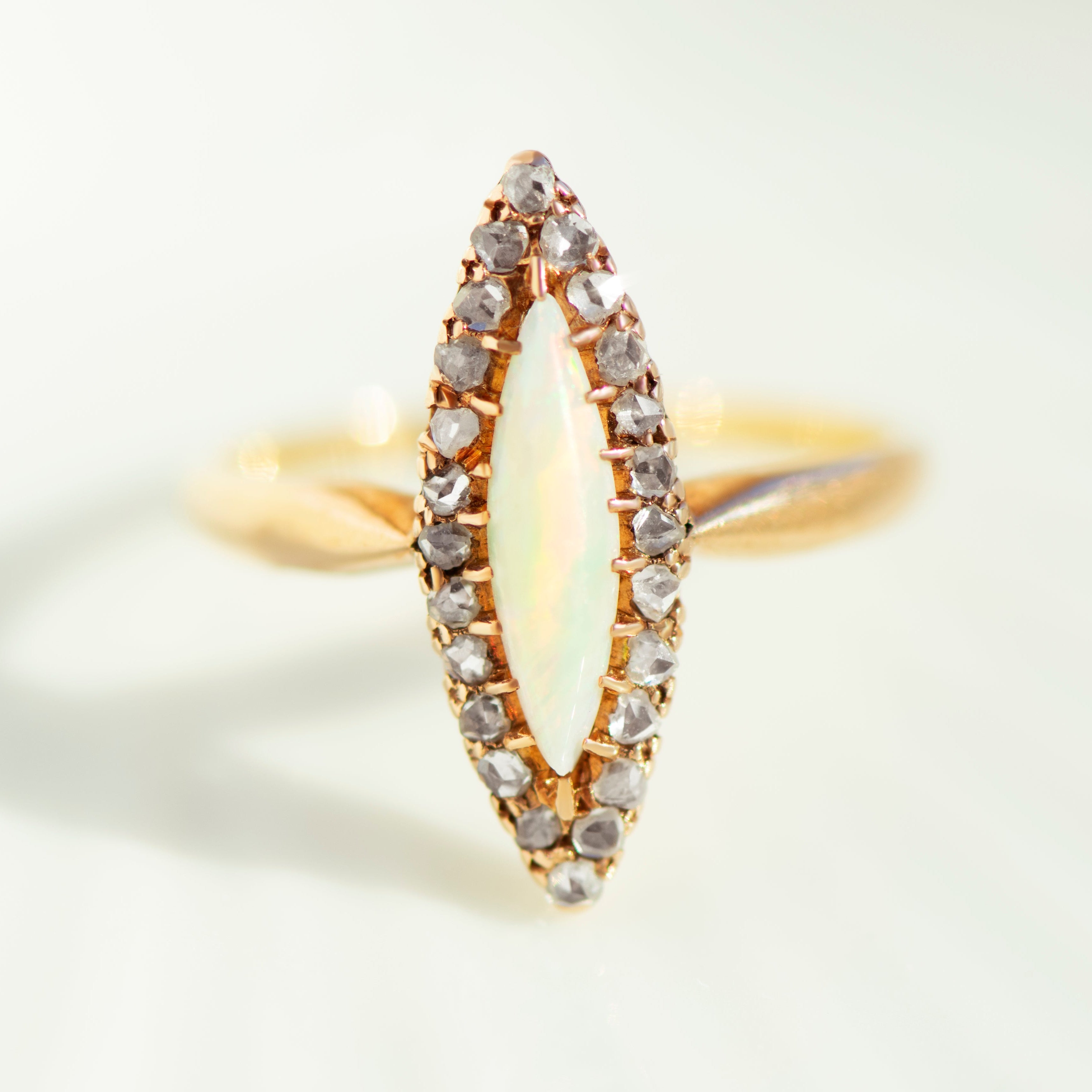 Front view symmetrical navette opal ring with diamond border