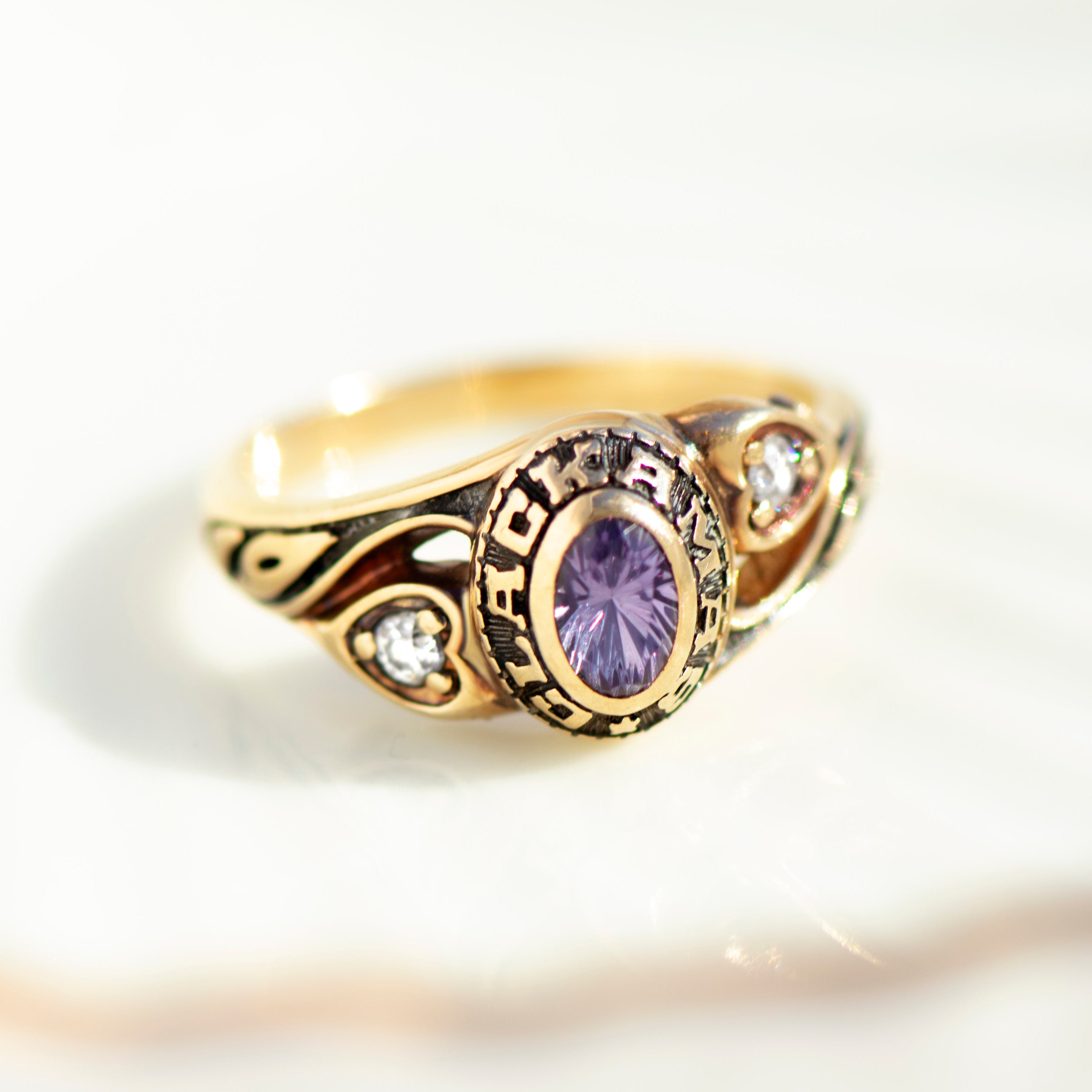Front view of 1986 Clackamas class ring featuring oval purple stone and heart-shaped zircon accents