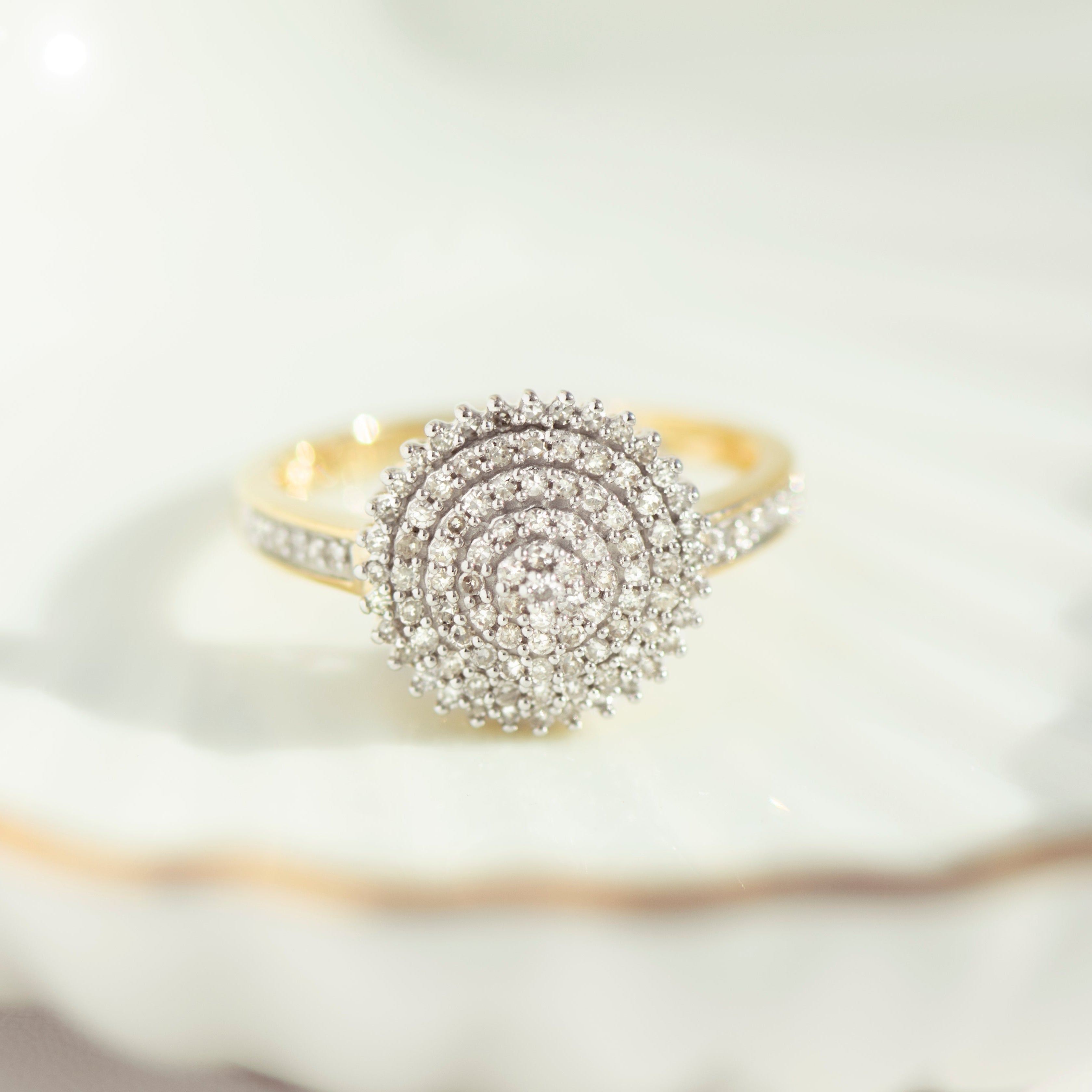 Front view of 14 karat yellow gold diamond cluster ring with spiral stone pattern