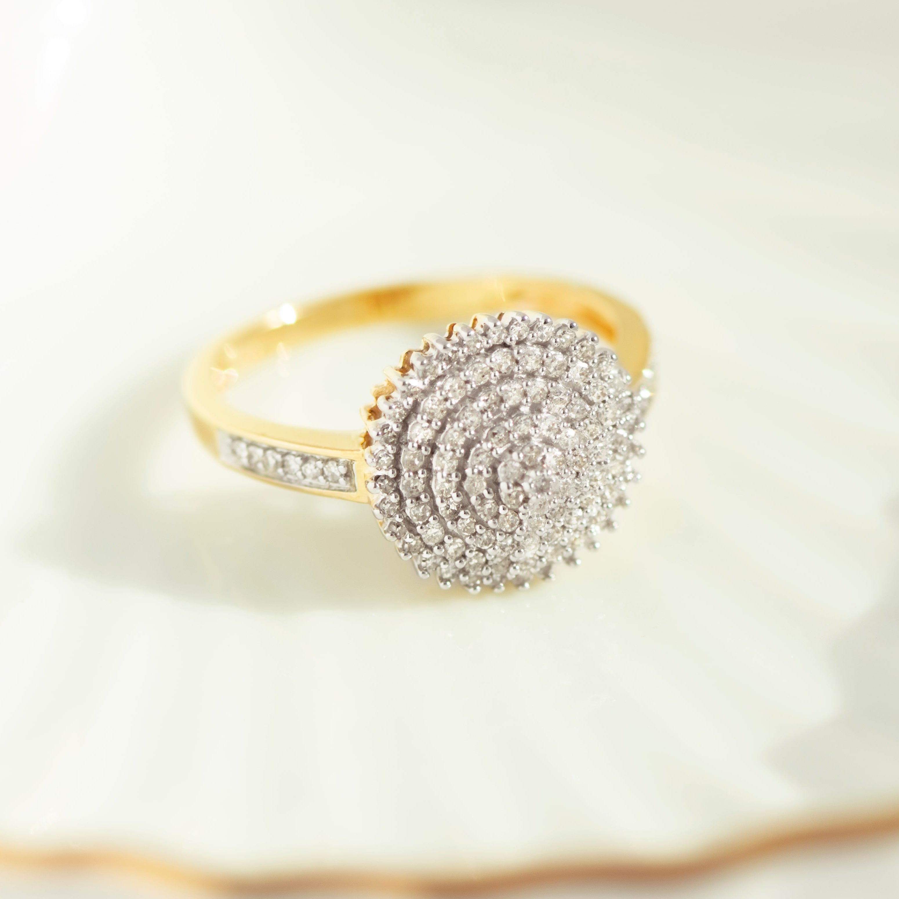 Close-up of textured 14k yellow gold diamond cluster ring with channel-set band details