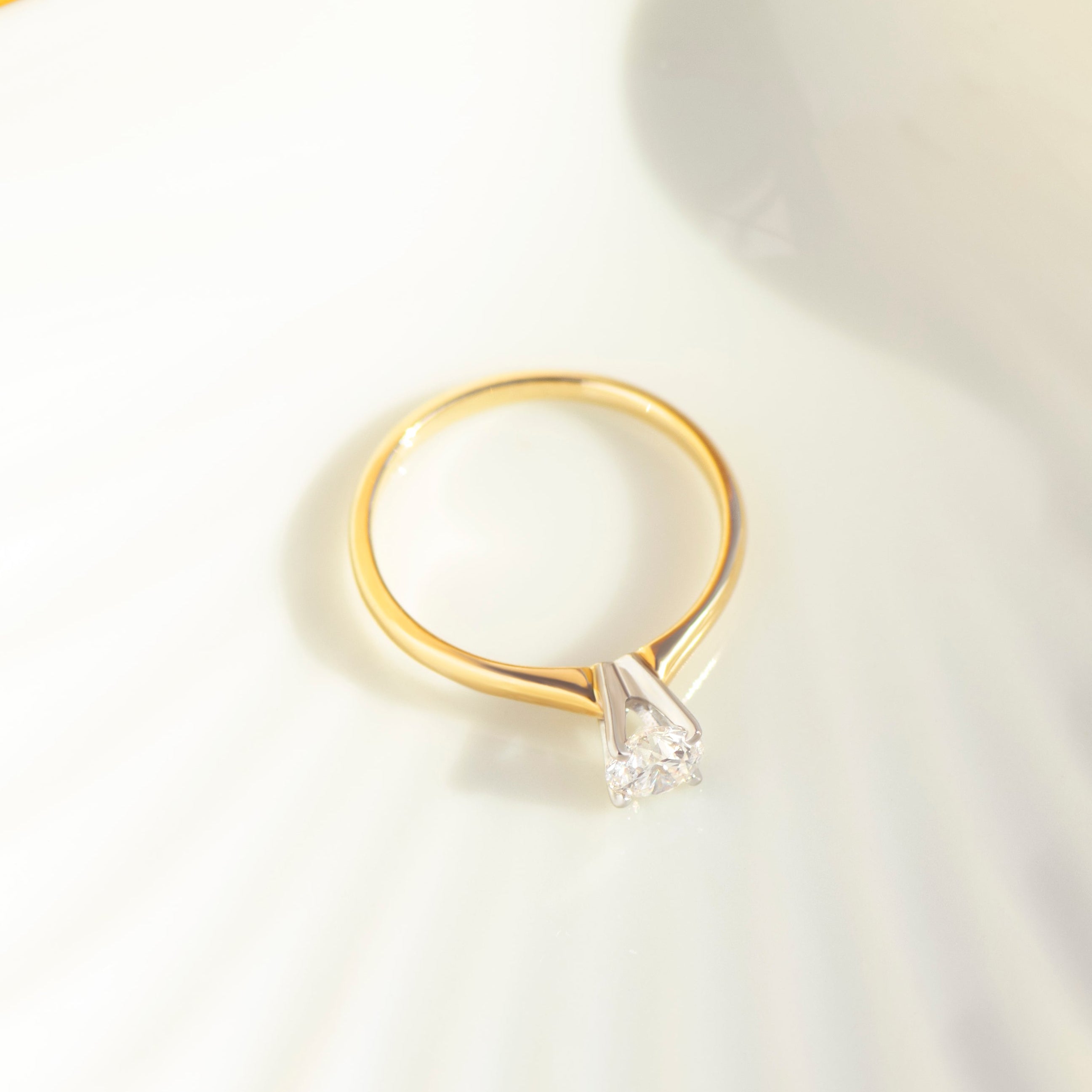Top view of tapered 14k yellow gold band with white gold diamond solitaire setting