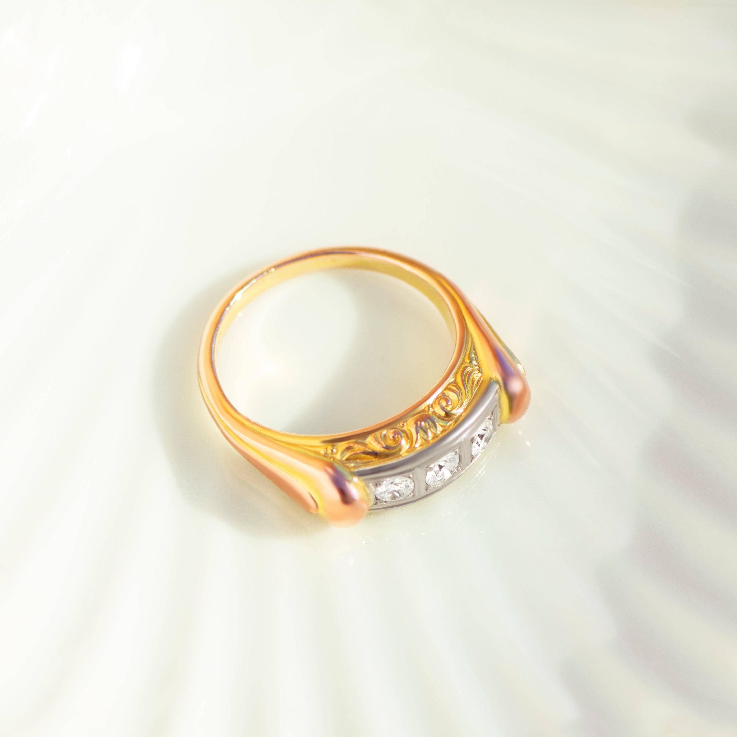 Side profile of asymmetrical antique diamond ring with intricate yellow gold scrollwork and smooth red gold accents