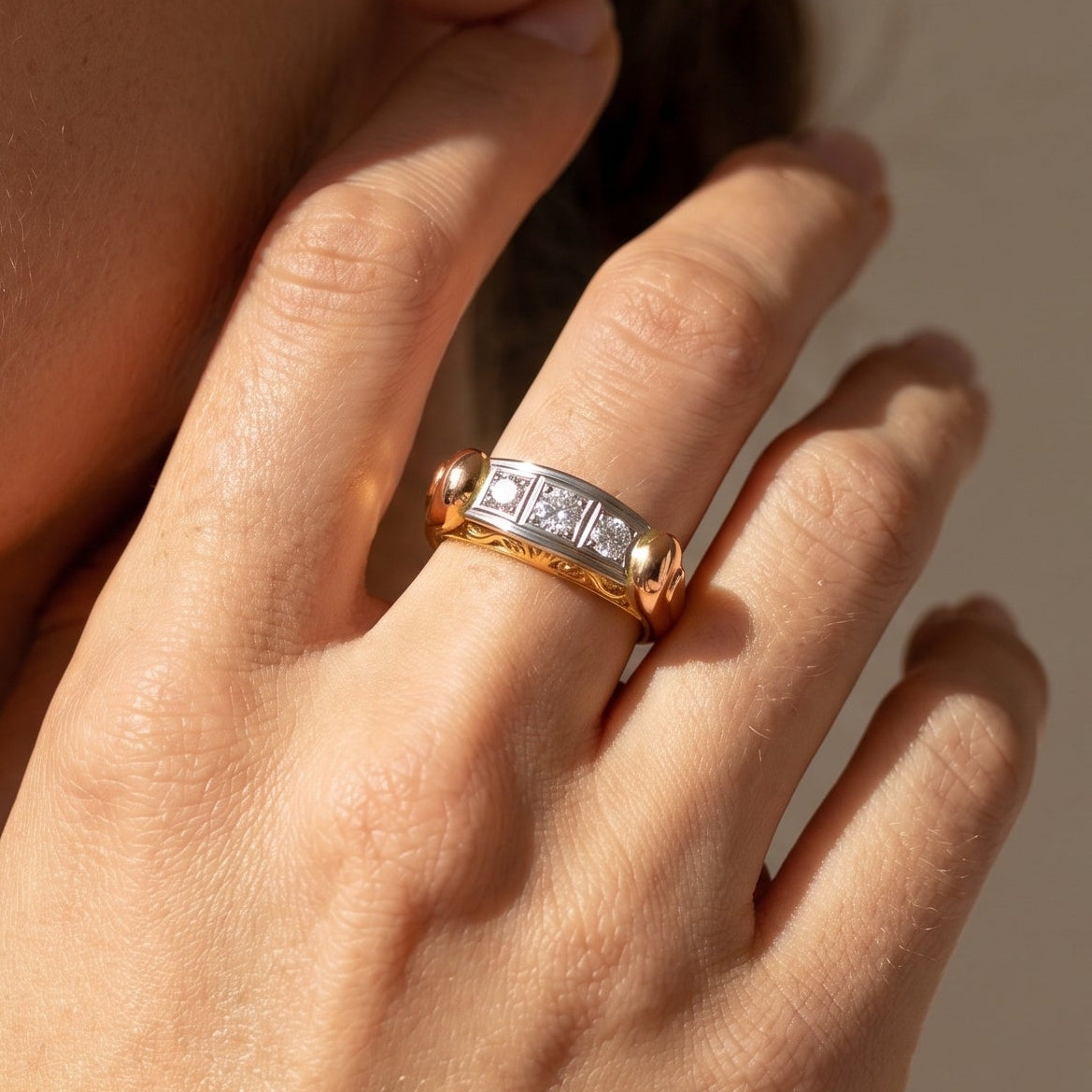 Tri-color gold diamond ring worn on finger showing scale of three stone white gold setting against yellow red gold band