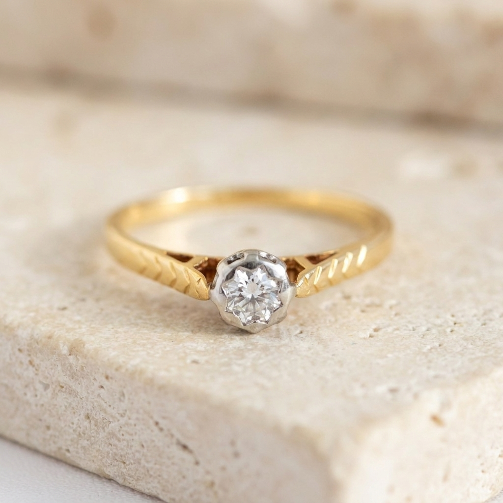 Close-up of 750 yellow gold diamond solitaire ring featuring white gold bezel and chevron engraving