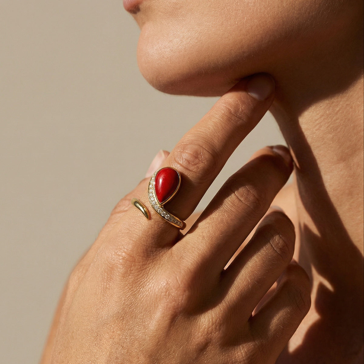 Woman wearing 18k gold ring with large coral cabochon and diamond band