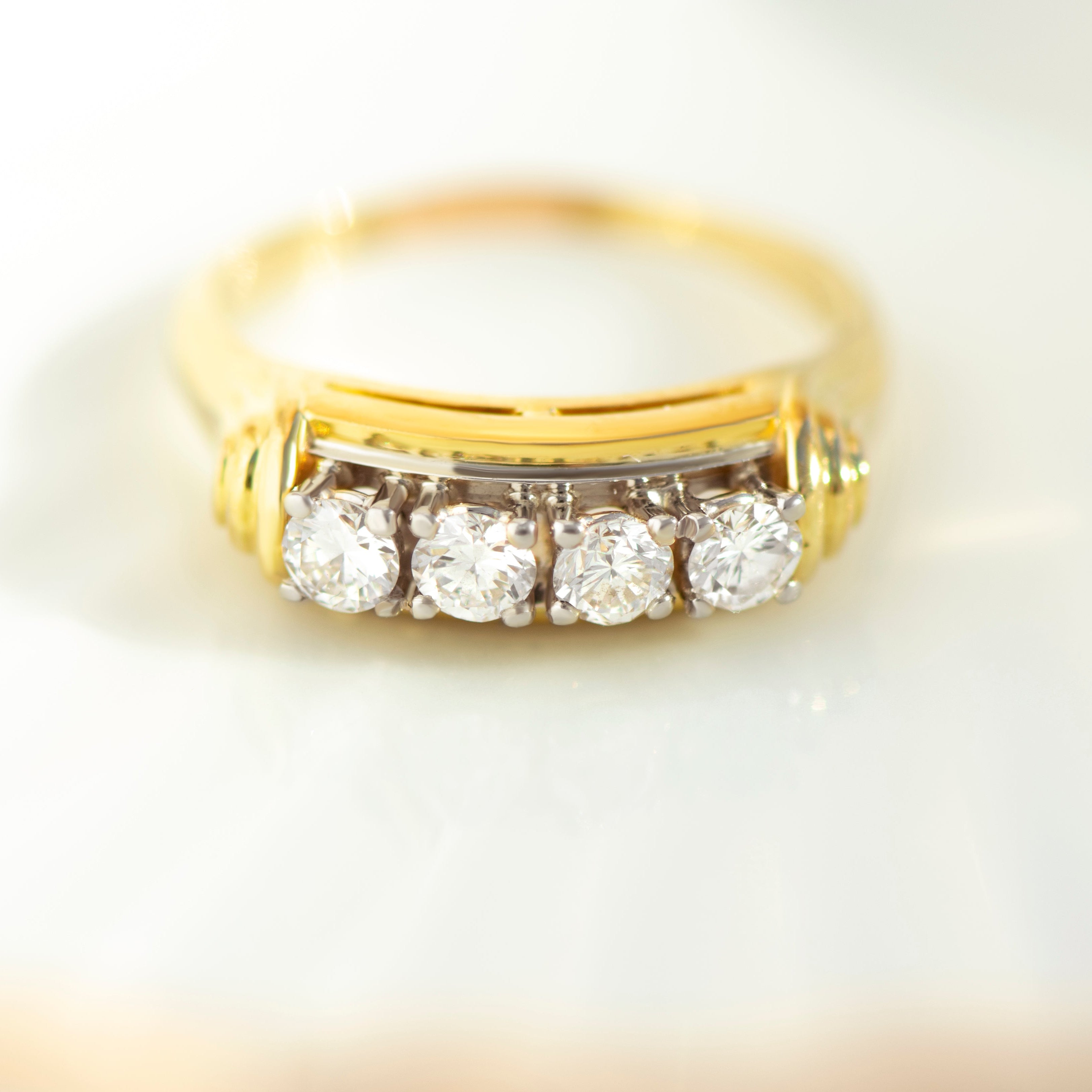 Close-up of 18k yellow gold ring featuring four row-set brilliant diamonds