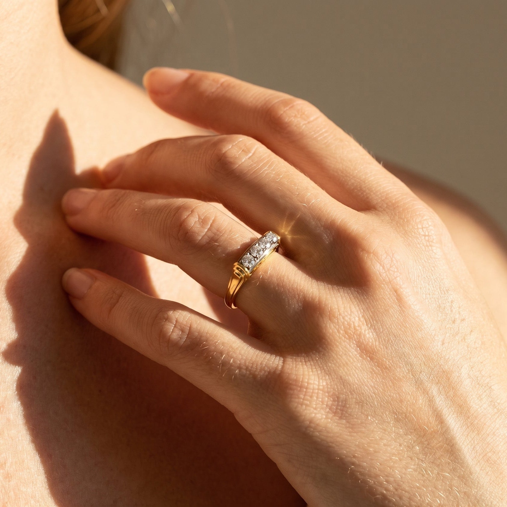 Woman wearing 18k yellow gold ring with four row-set diamonds